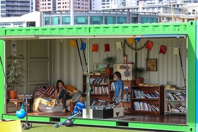 Tijdelijke bibliotheek in een groene container met boeken en bezoekers