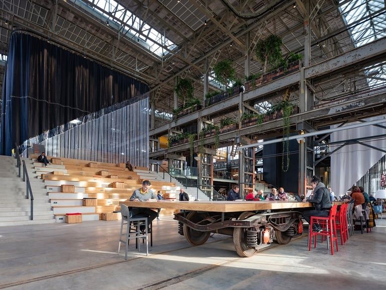 Industriële bibliotheekruimte met leestafels, tribune en spoorrails