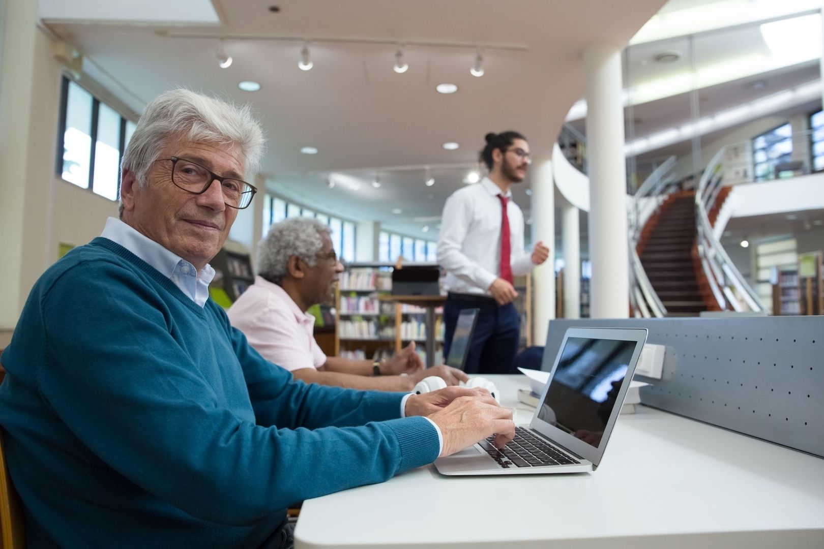 Ouderen werken met een laptop in een koele bibliotheekruimte
